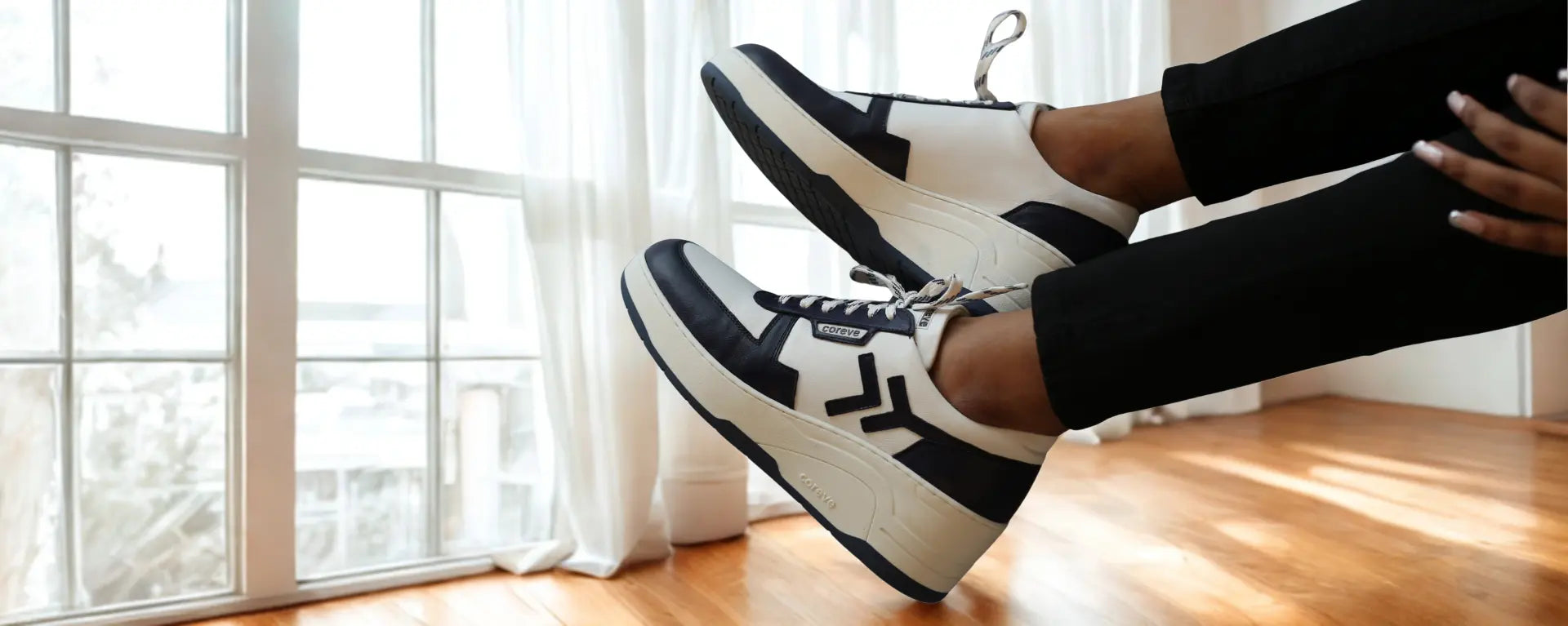 wearing black and white sneakers with a blurred indoor background